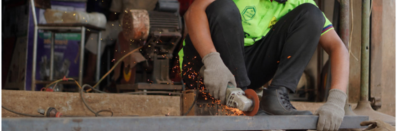 Youth apprentice cutting metal with sparks in a mechanical workshop