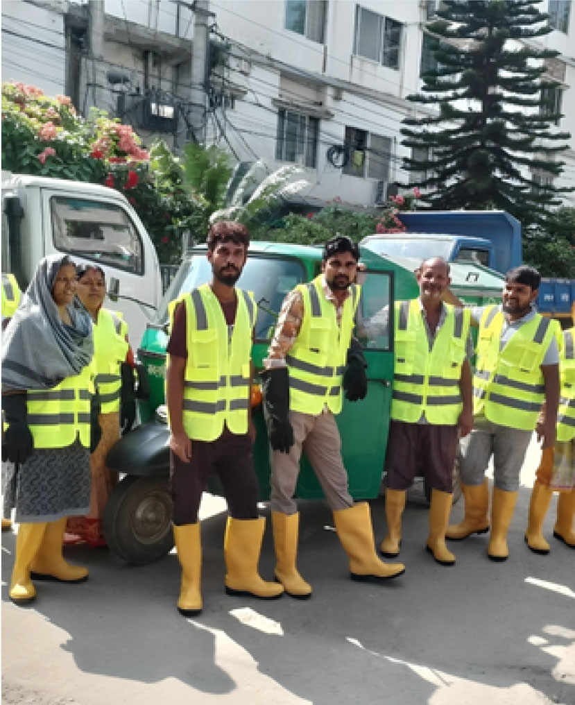 Sanitation workers wearing high-visibility vests and safety boots with vehicle