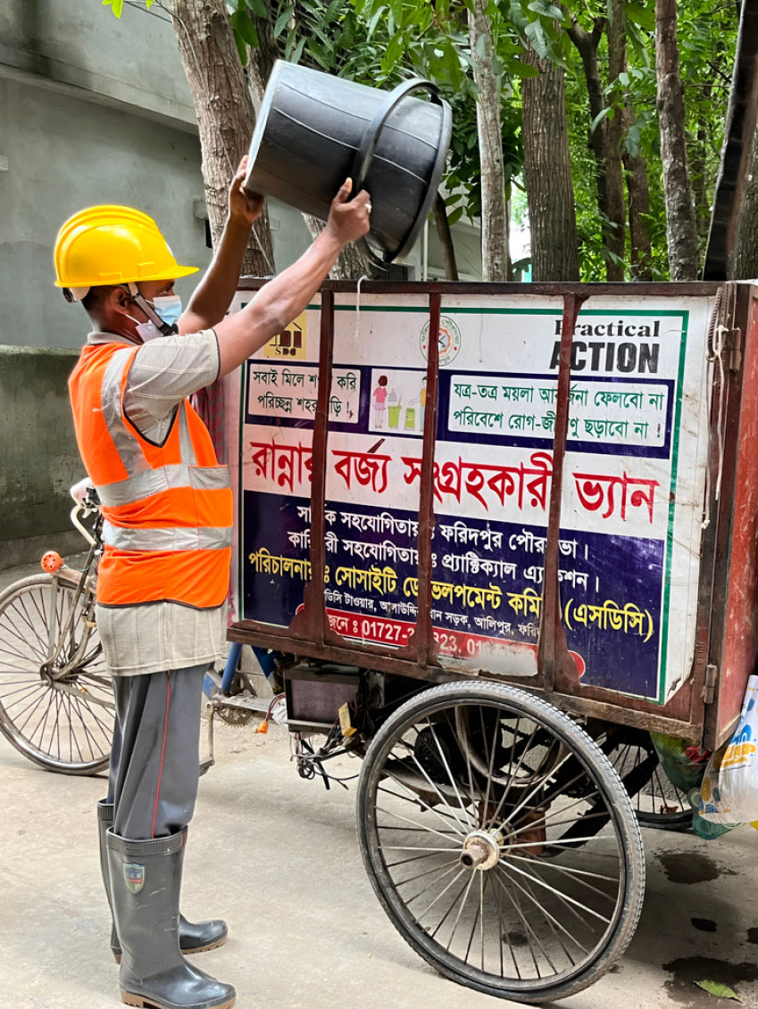 Sanitation worker loading kitchen waste into collection van