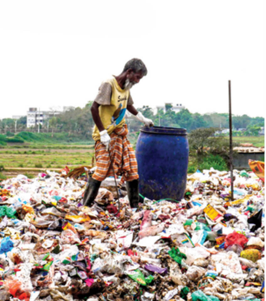 Waste worker carrying a large blue drum amidst plastic waste dumpsite